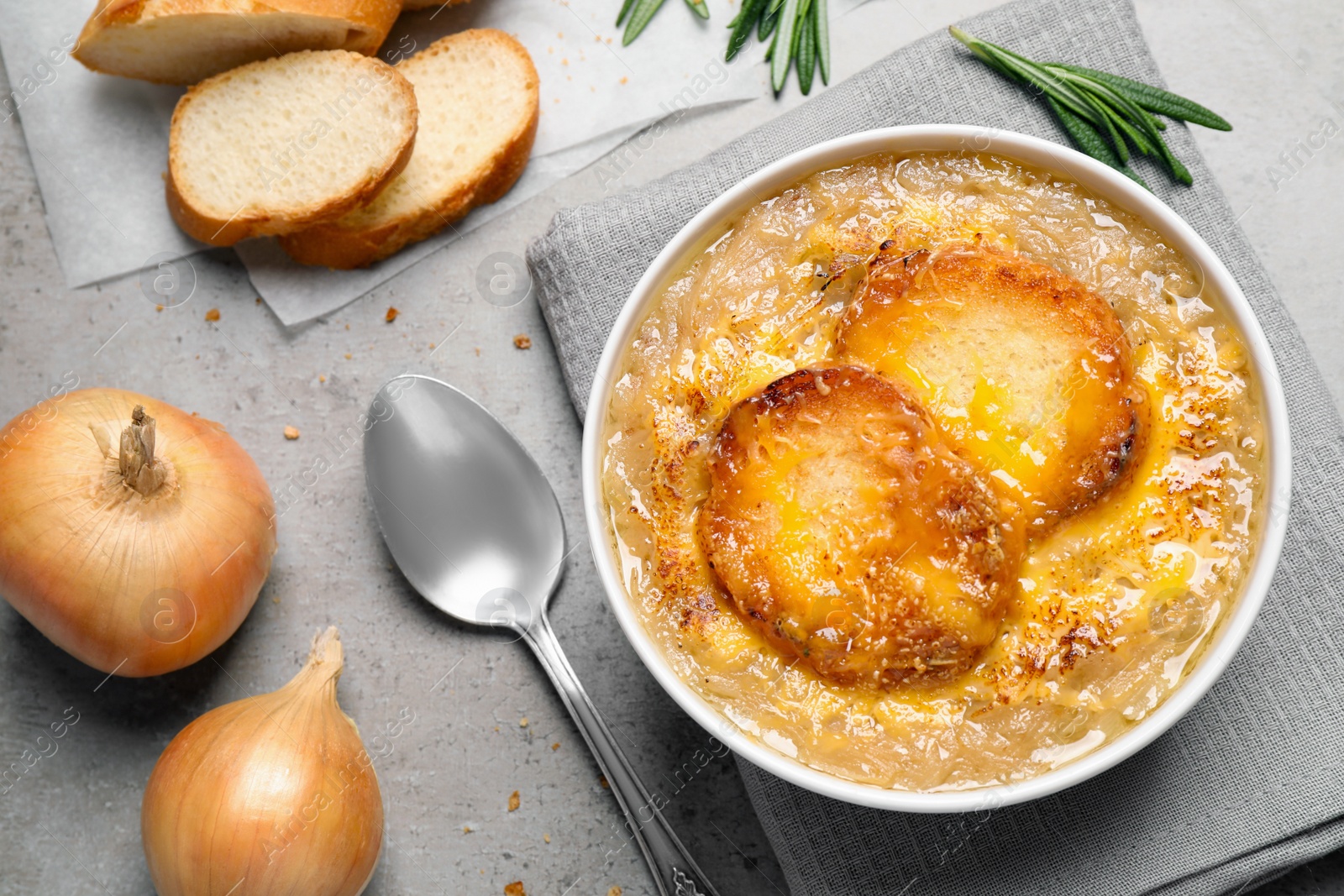 Photo of Tasty homemade french onion soup served on grey table, flat lay