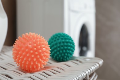 Photo of Dryer balls on wicker basket near washing machine in laundry room, closeup