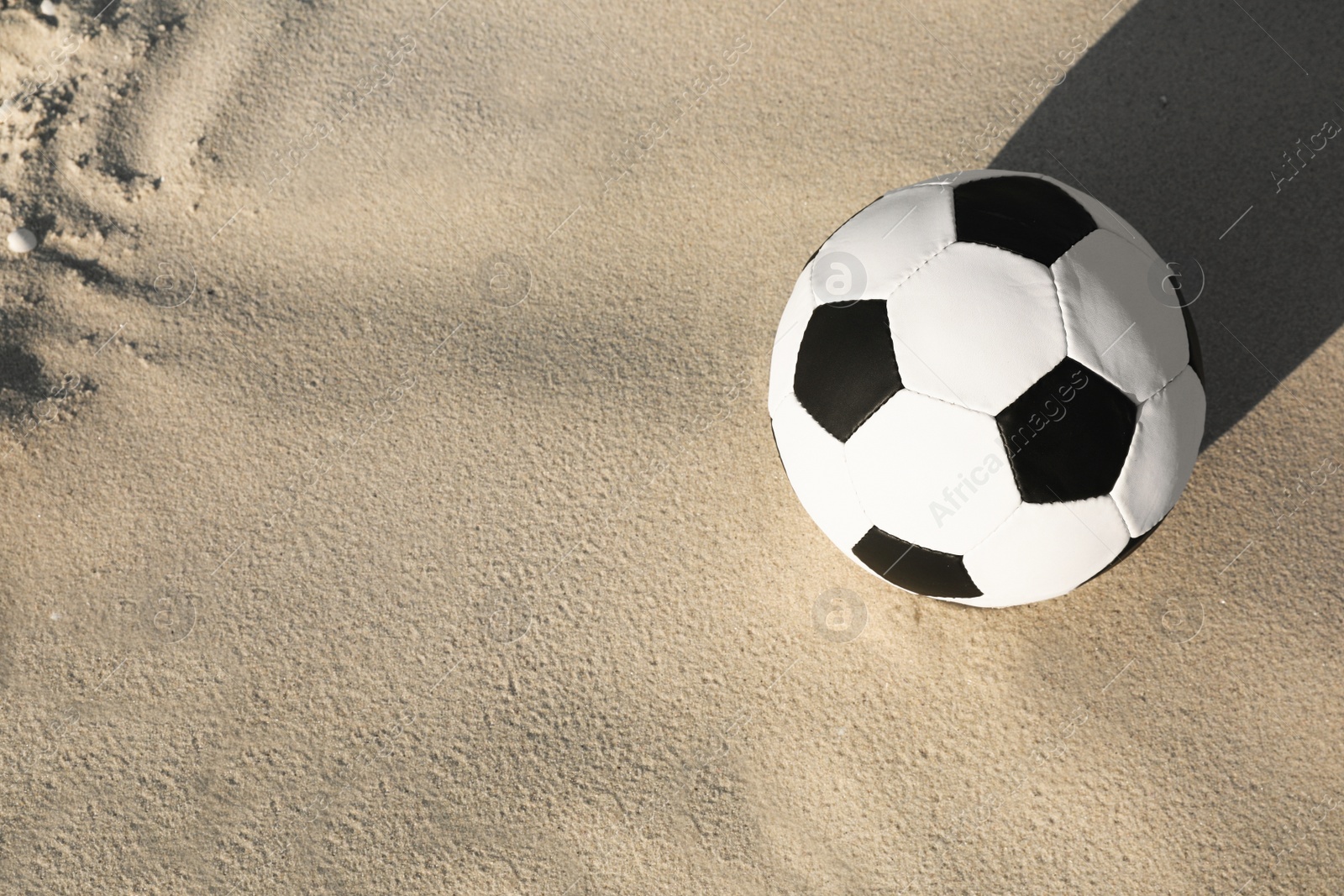 Photo of Soccer ball on sand, above view with space for text. Football equipment