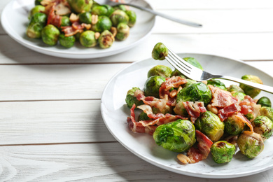 Delicious Brussels sprouts with bacon on white wooden table