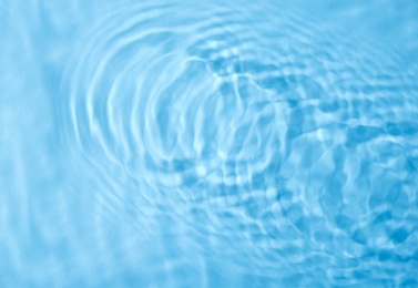 Concentric waves on blue water surface after falling drops, top view