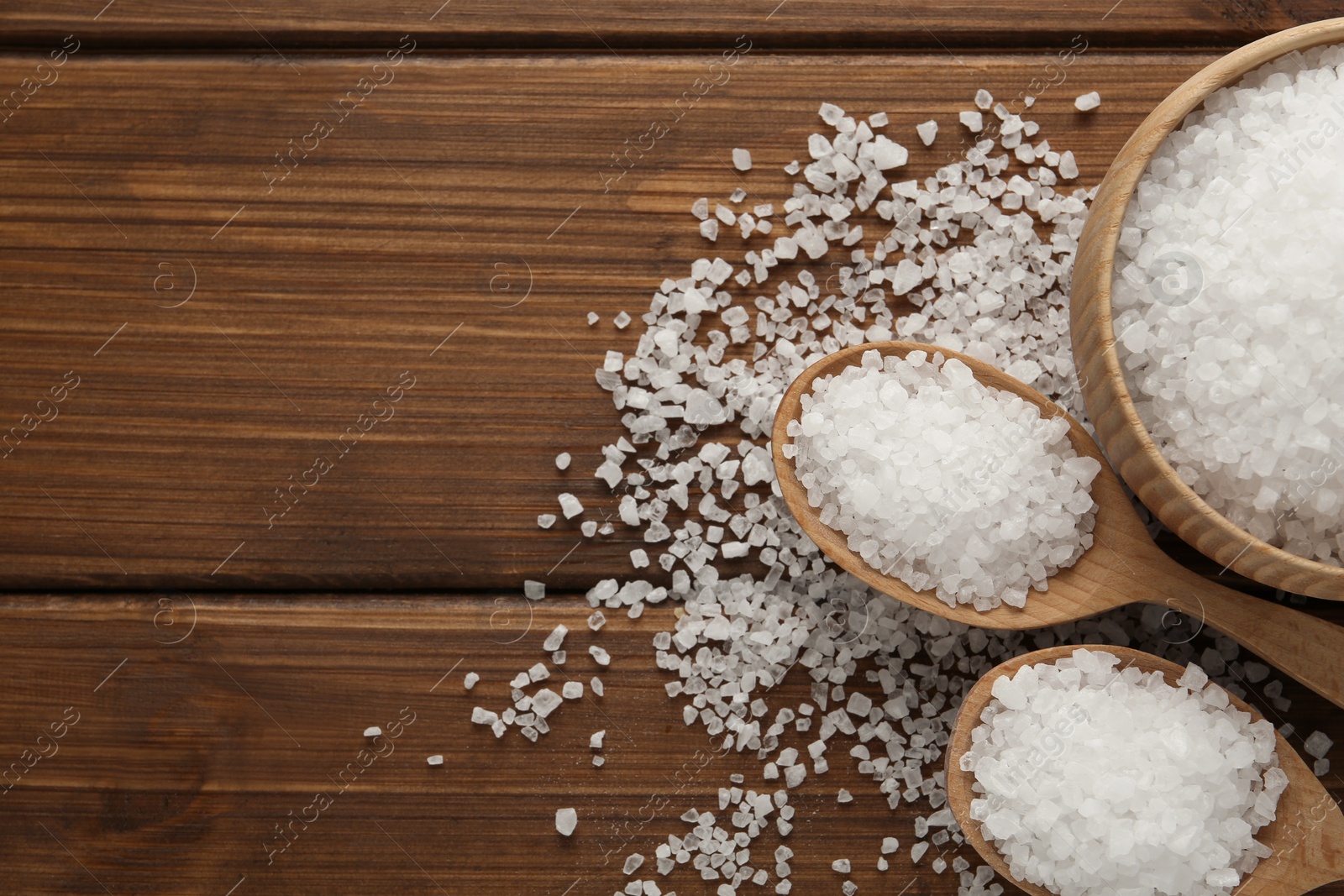 Photo of Natural sea salt on wooden table, flat lay. Space for text