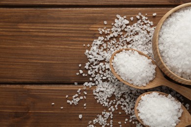 Natural sea salt on wooden table, flat lay. Space for text