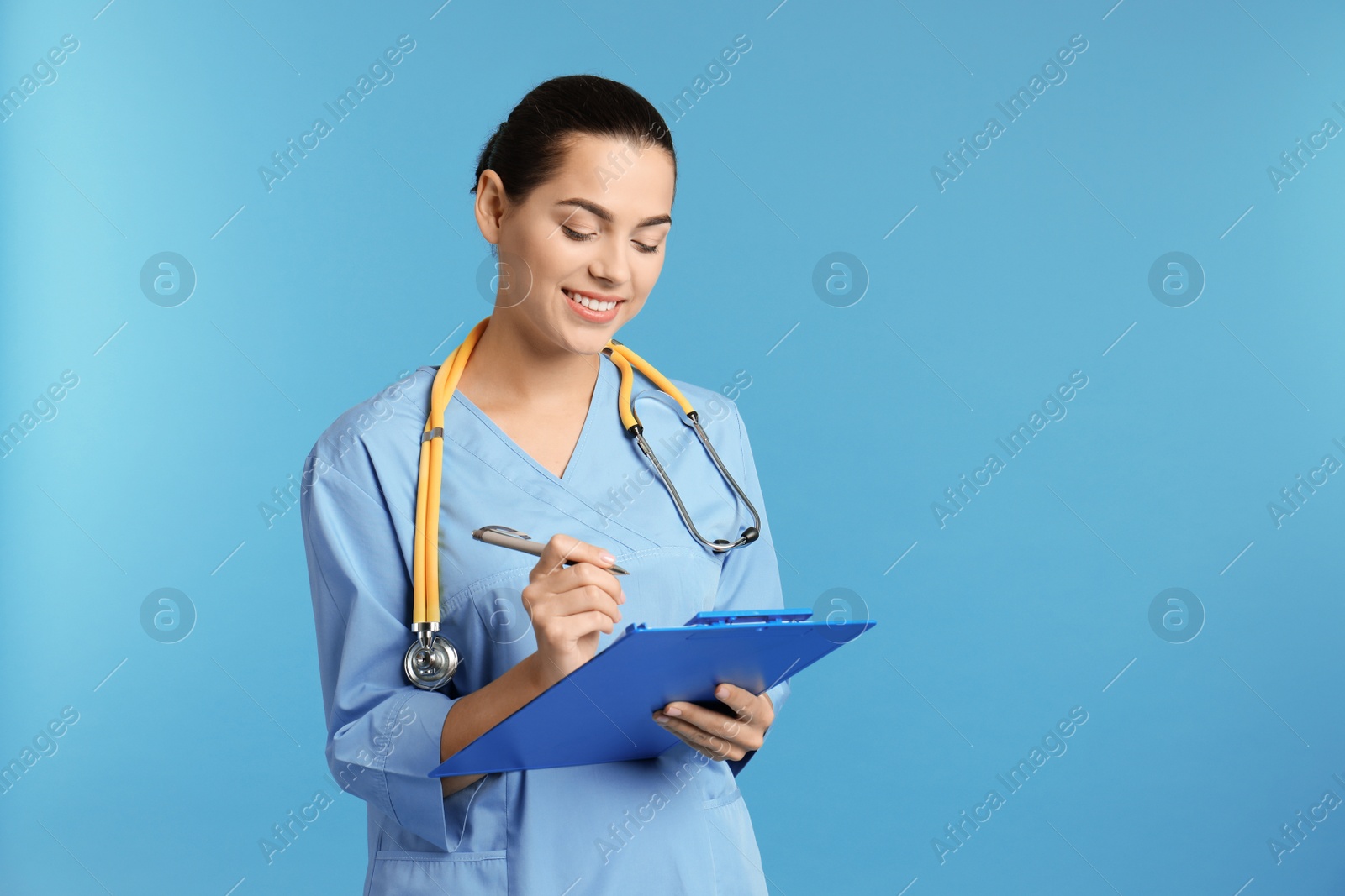 Photo of Portrait of young medical assistant with stethoscope and clipboard on color background. Space for text