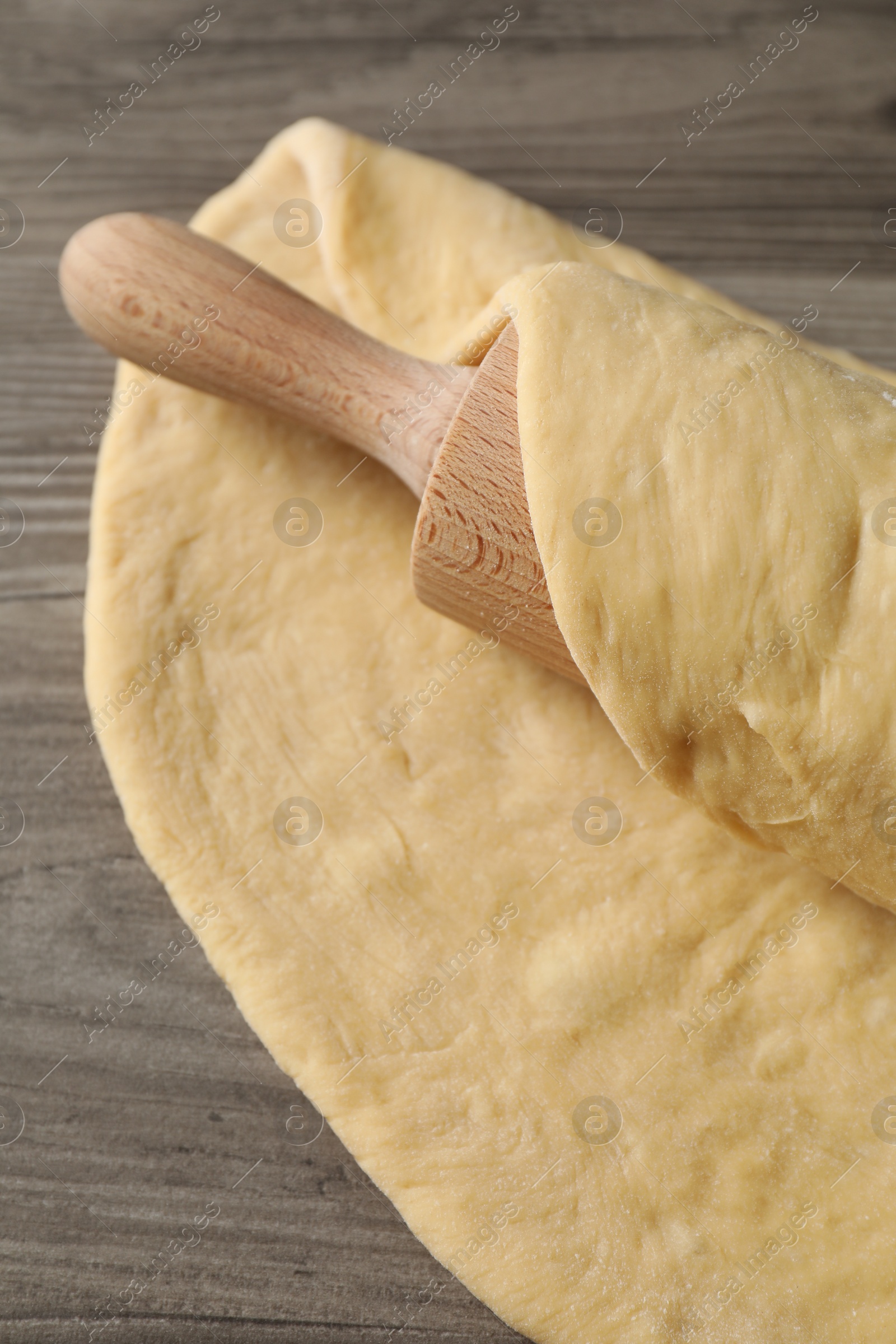 Photo of Raw dough and rolling pin on wooden table