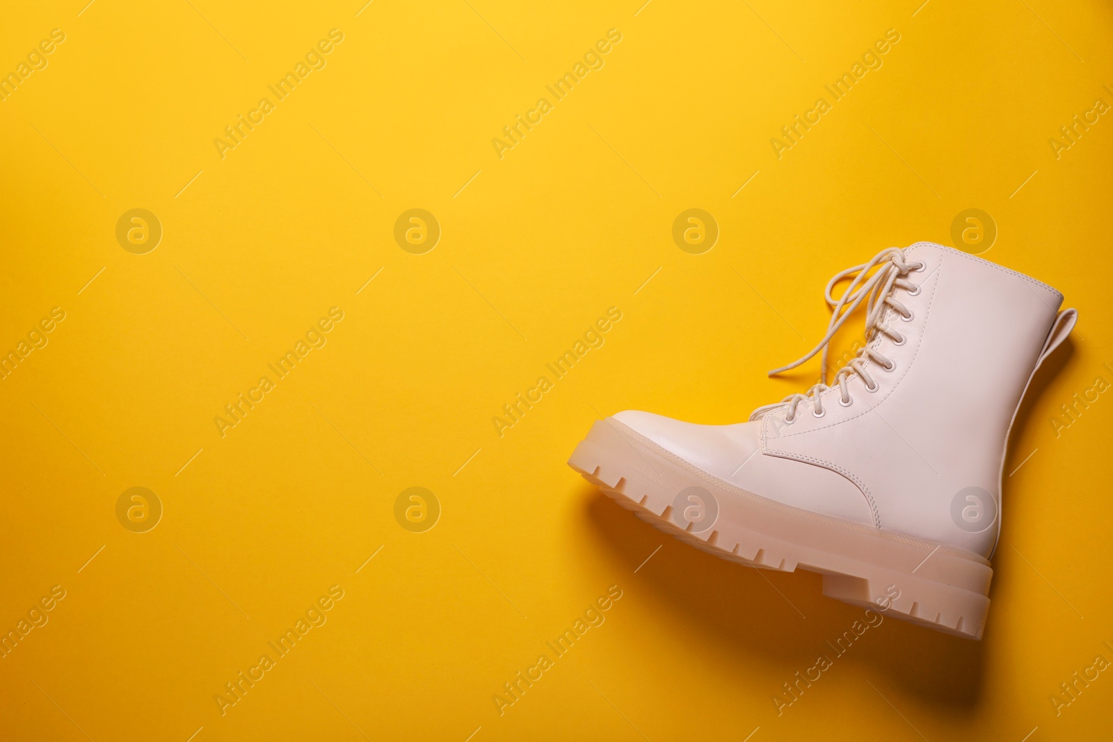 Photo of Stylish leather shoe on yellow background, top view. Space for text