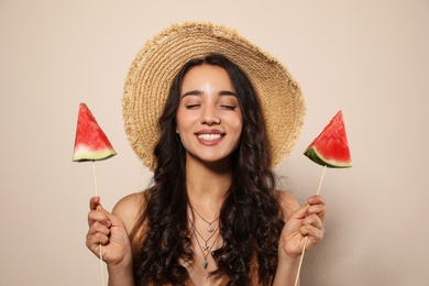 Beautiful young woman with watermelon on beige background