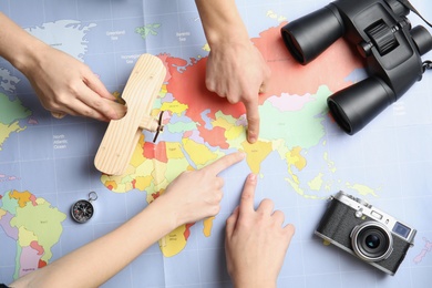 Women with tourist items planning vacation on world map, top view. Travel agency