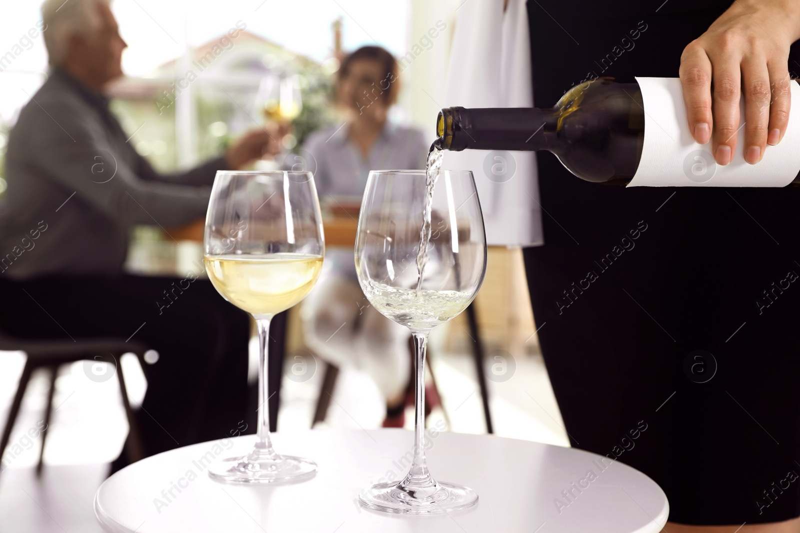 Photo of Waitress pouring wine into glass in restaurant, closeup