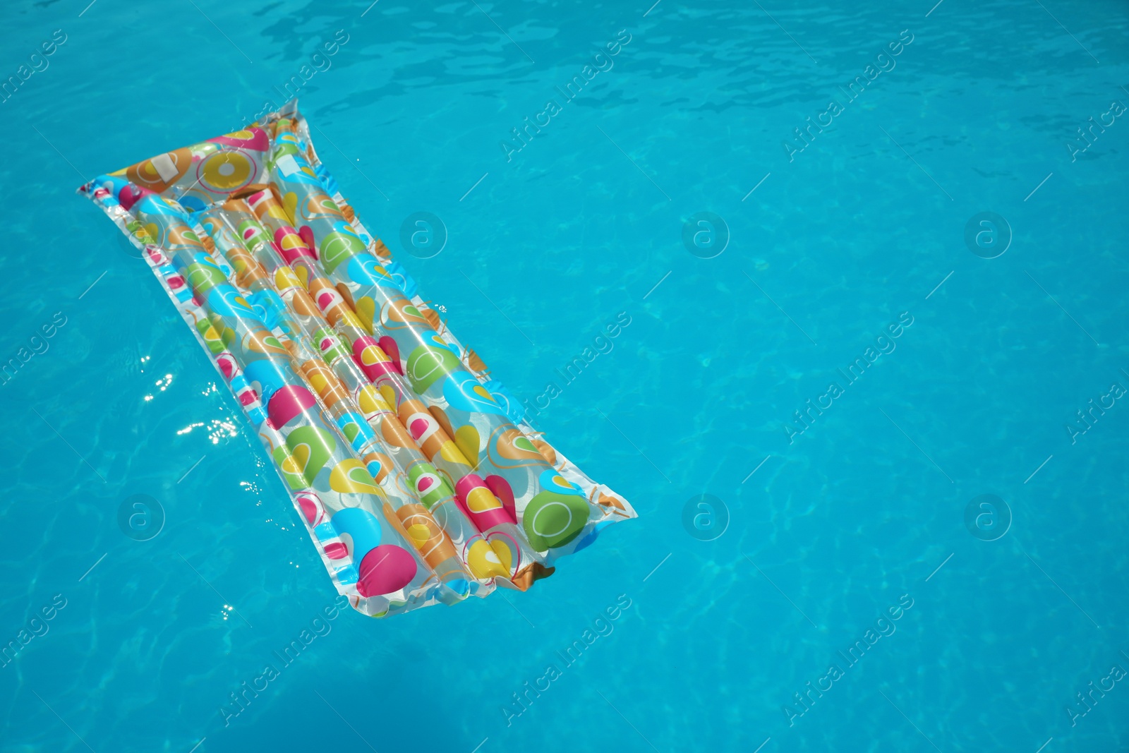 Photo of Colorful inflatable mattress floating in swimming pool on sunny day. Space for text