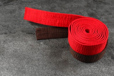 Photo of Red and brown karate belts on gray textured background, space for text