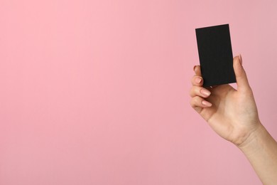 Photo of Woman with blank black business card on pink background, closeup. Mockup for design