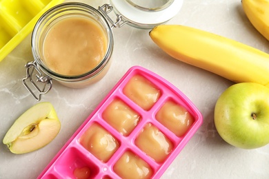 Photo of Flat lay composition with ice cube tray and jar of baby food on gray background