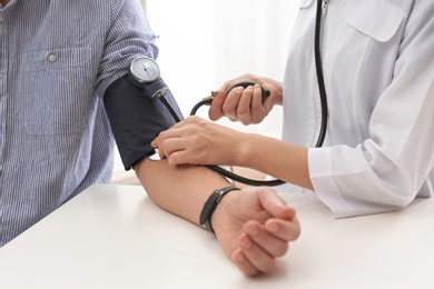 Photo of Doctor checking patient's blood pressure in hospital, closeup. Cardiology concept