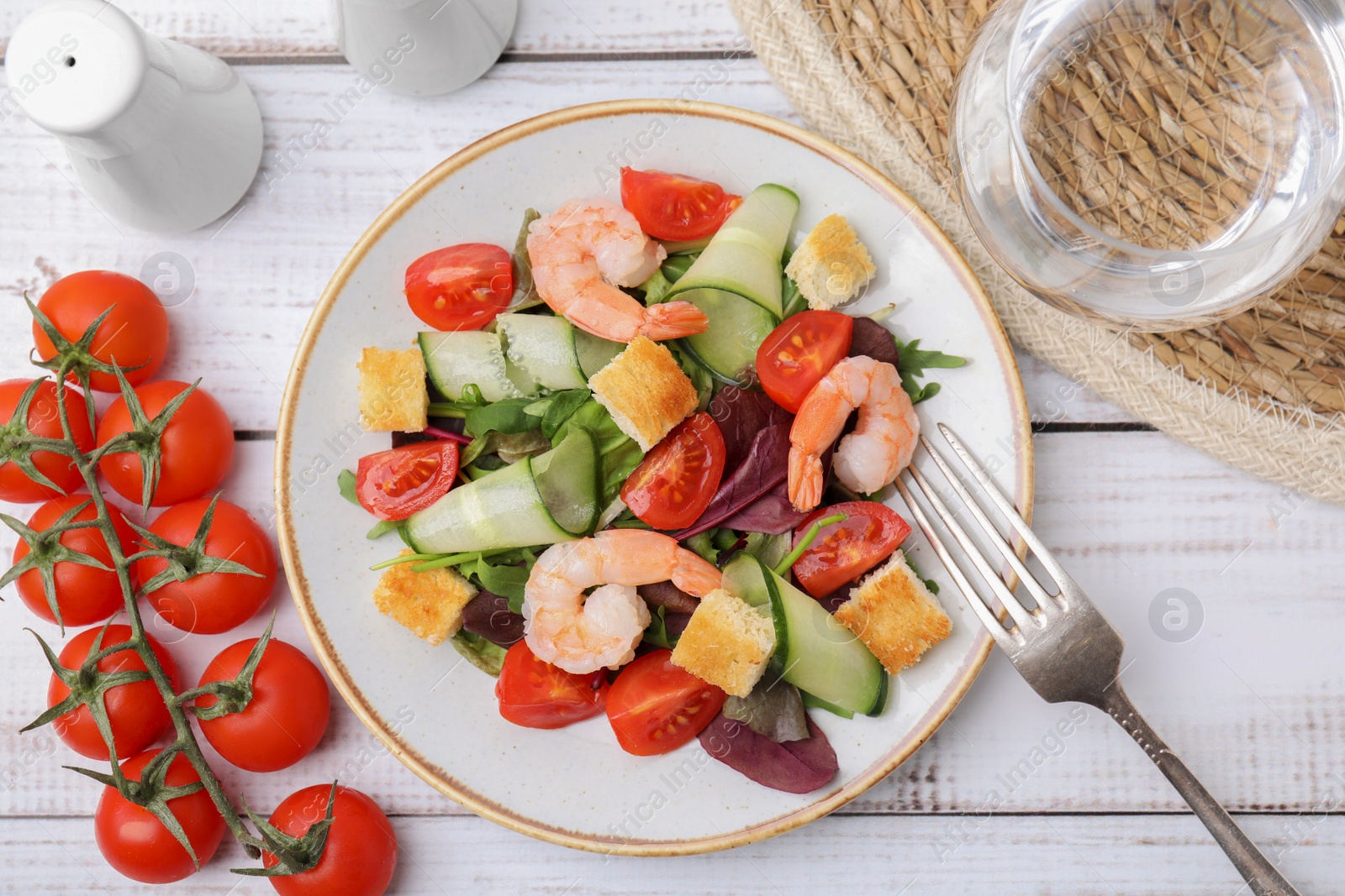 Photo of Tasty salad with croutons, tomato and shrimps served on white wooden table, flat lay