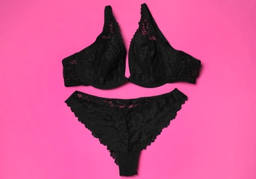 Photo of Set of black lace lingerie on pink background, flat lay