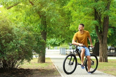 Handsome man with modern bicycle in park