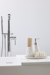 Different personal care products and accessories on bath tub in bathroom