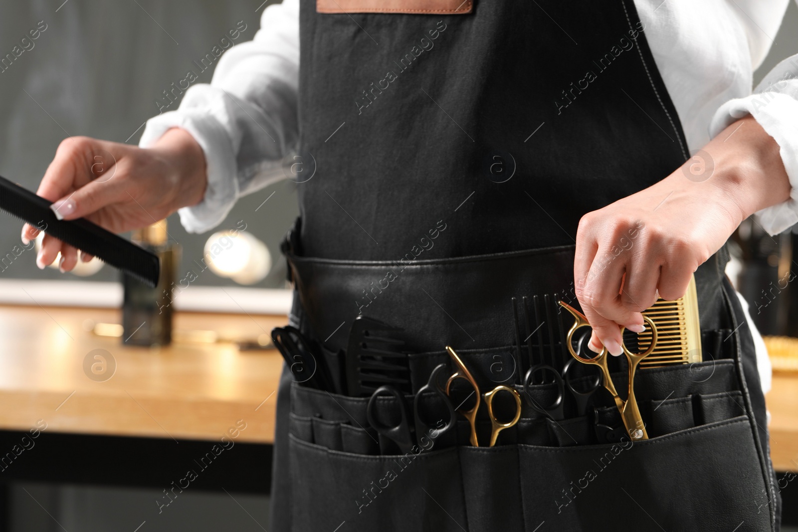 Photo of Hairstylist with professional tools in waist pouch in salon, closeup