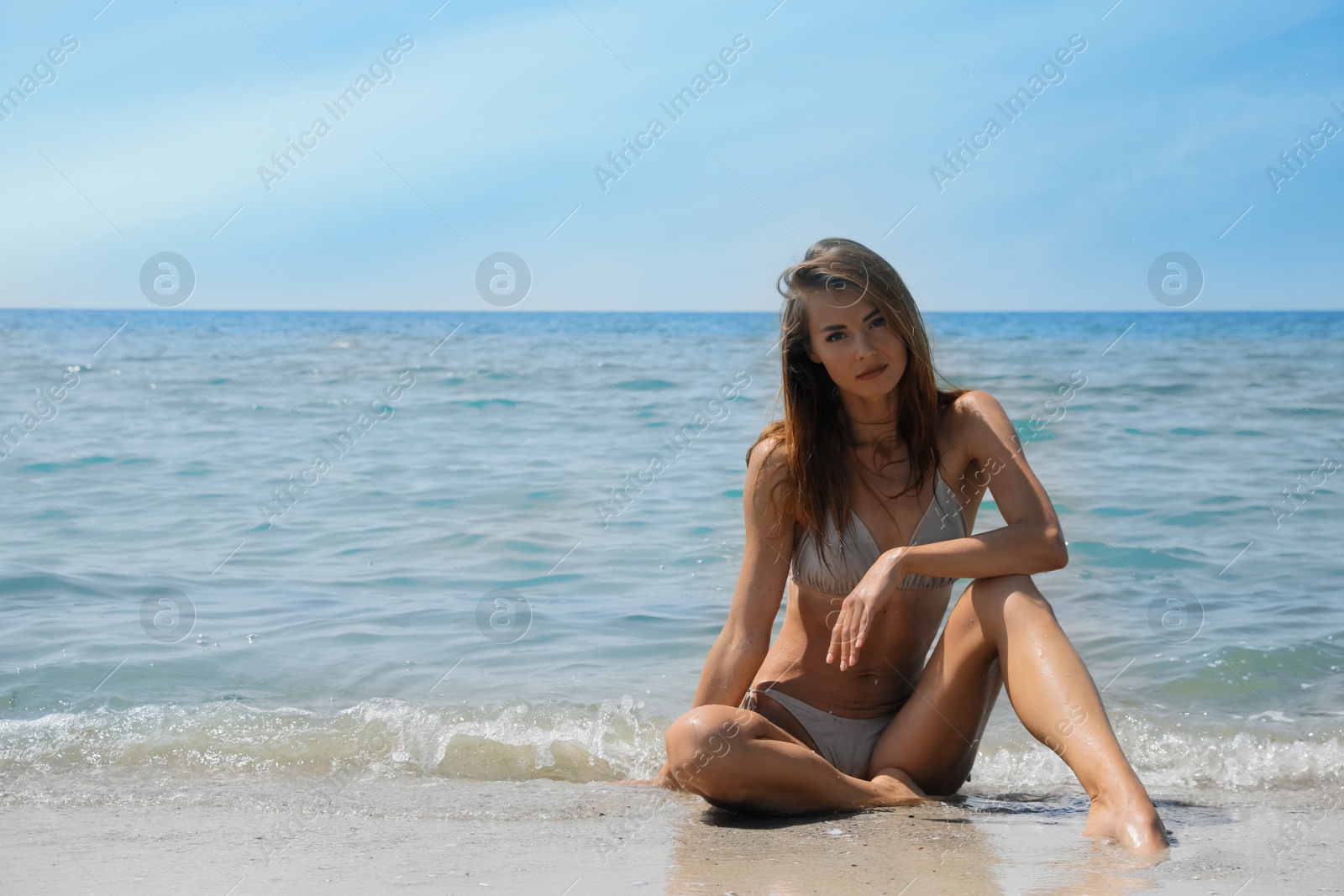 Photo of Attractive woman in bikini sitting on seashore