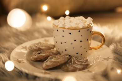 Photo of Cup of hot drink with marshmallows and cookies on plate indoors, closeup. Christmas atmosphere