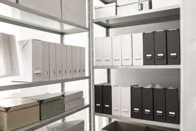 Photo of Folders and boxes with documents on shelves in archive
