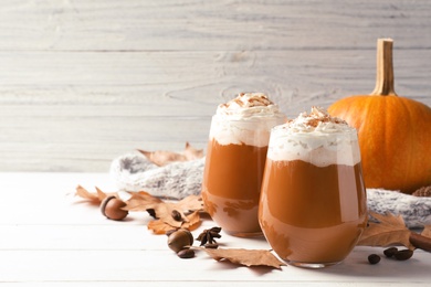 Glasses with tasty pumpkin spice latte on wooden table. Space for text