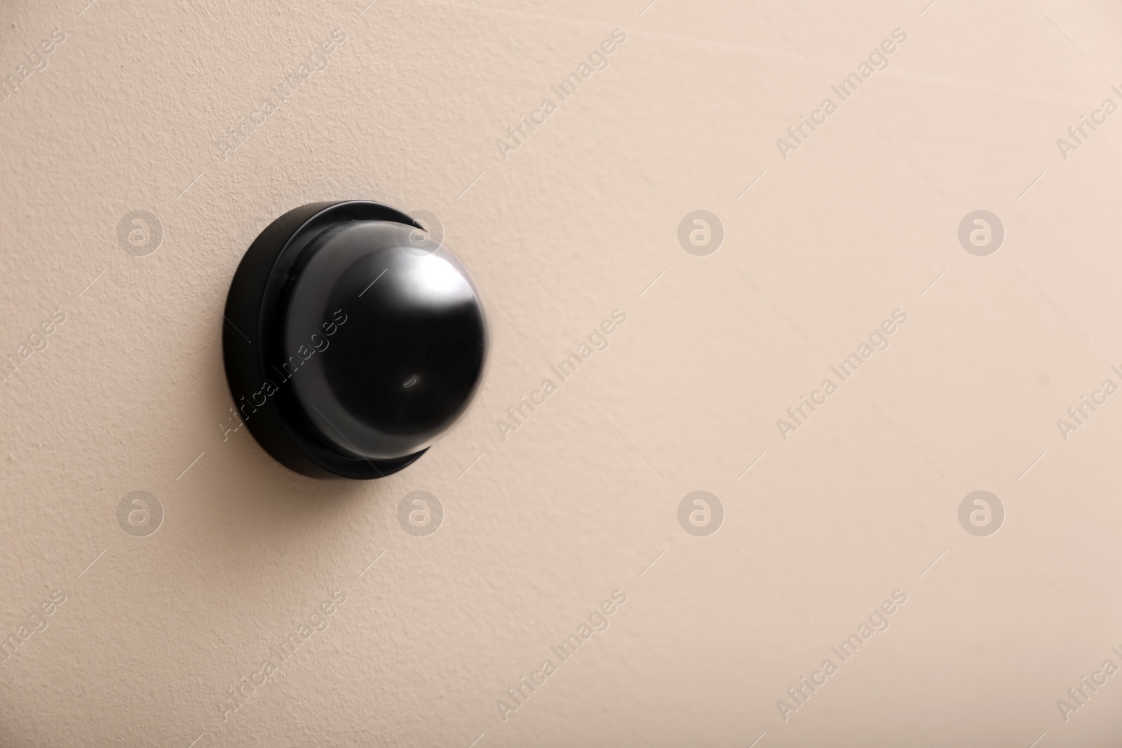 Photo of Modern CCTV security camera on beige wall. Space for text