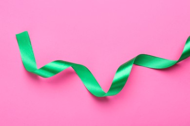 Photo of Beautiful ribbon on pink background, top view