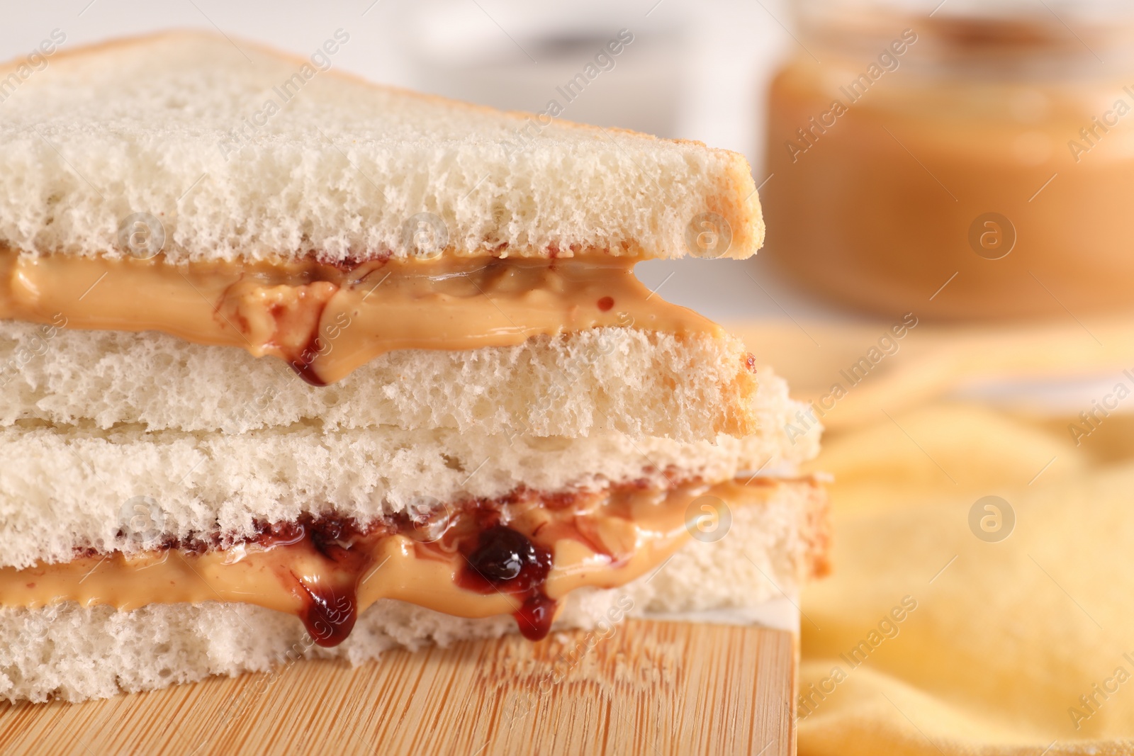 Photo of Sandwich with tasty nut butter and jam on wooden board, closeup. Space for text