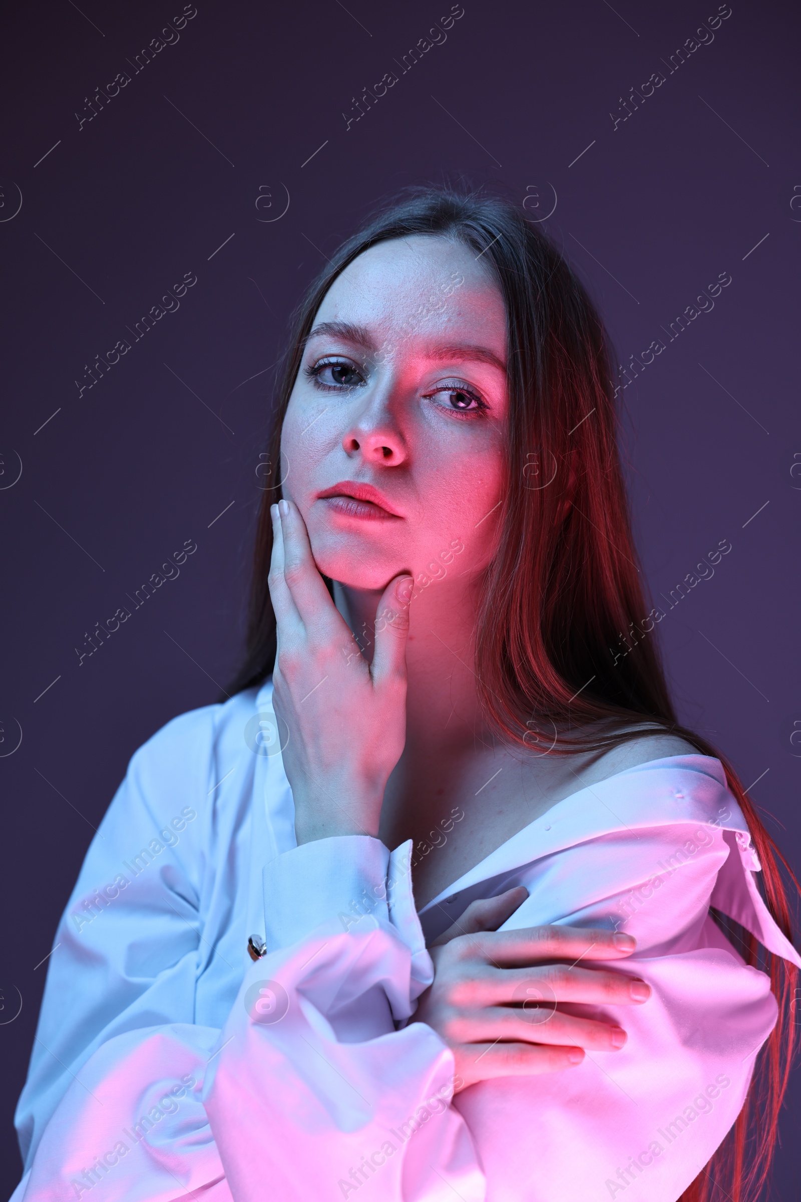 Photo of Fashionable portrait of beautiful young woman on purple background in neon lights