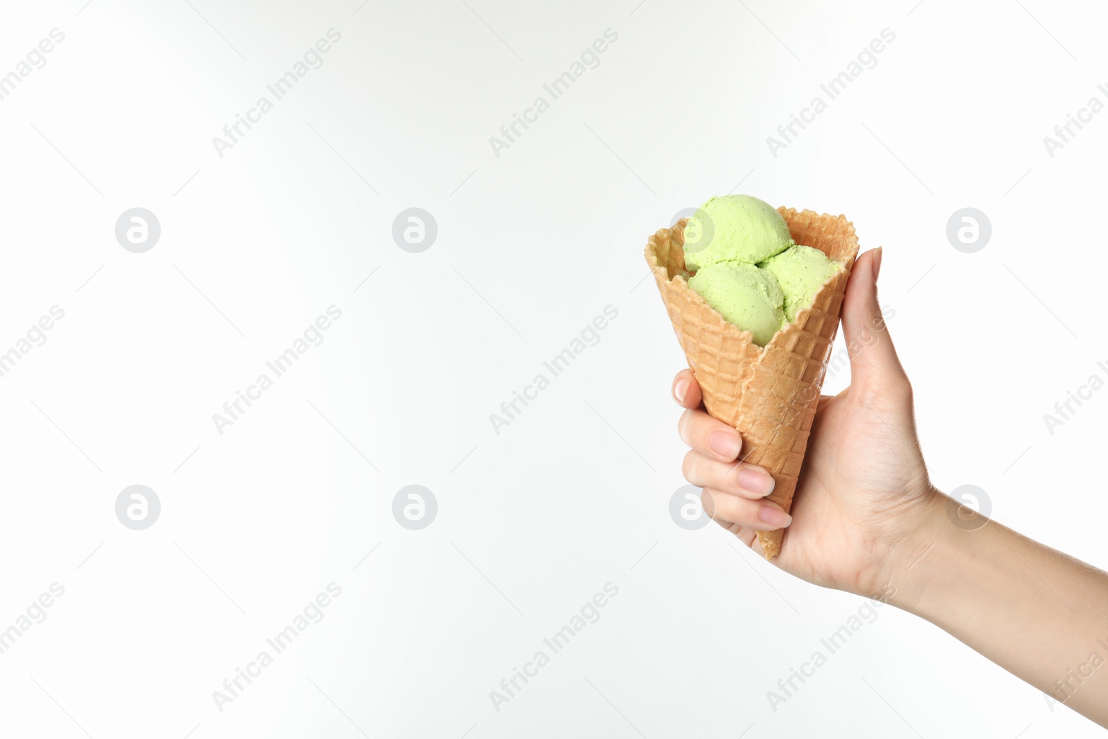 Photo of Woman holding delicious ice cream in waffle cone on white background, closeup