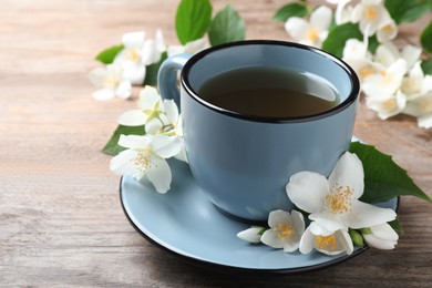 Cup of tea and fresh jasmine flowers on wooden table