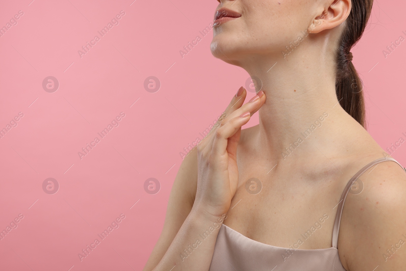 Photo of Woman touching her neck on pink background, closeup. Space for text