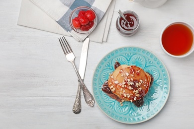 Photo of Delicious pancakes with jam and nuts served for breakfast on table, top view