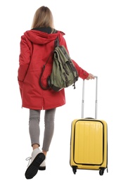 Photo of Woman with suitcase walking on white background, back view. Winter travel