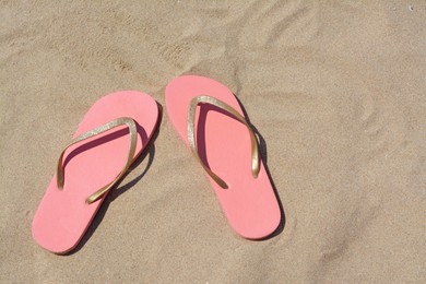 Photo of Stylish pink flip flops on sand, flat lay