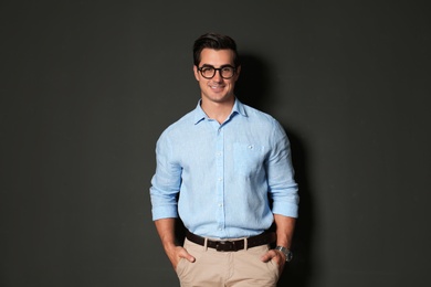 Photo of Handsome young man in stylish clothes with glasses on dark background