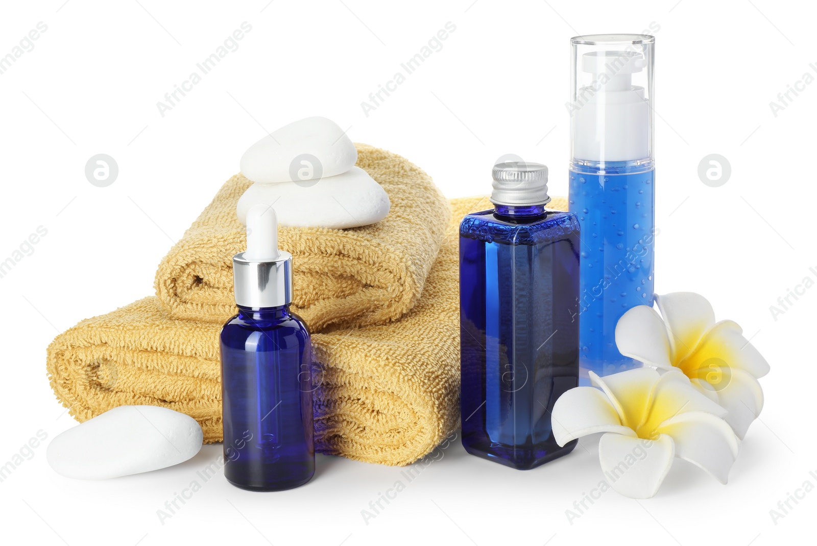 Photo of Spa composition. Bottles of cosmetic products, towels, stones and plumeria flowers isolated on white