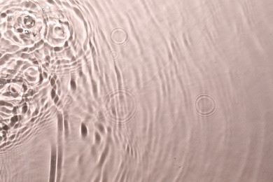 Rippled surface of clear water on beige background, top view