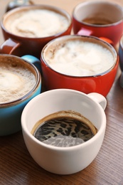 Cups of fresh aromatic coffee on wooden table