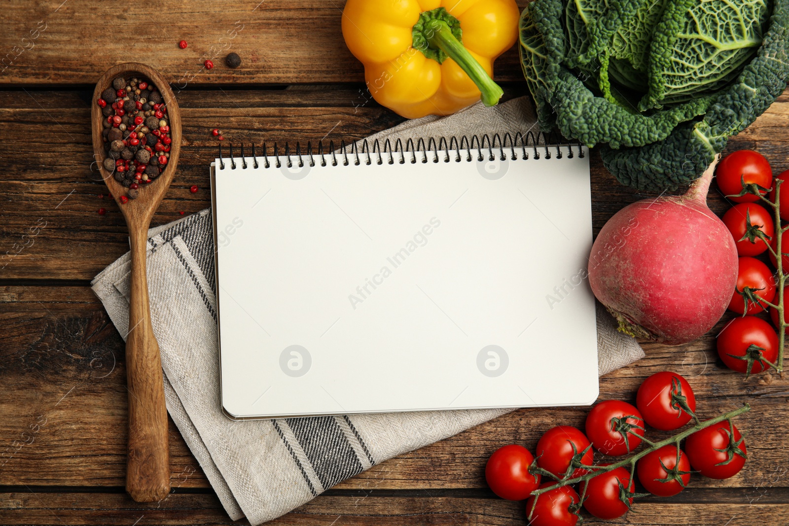 Photo of Recipe book surrounded by different ingredients on wooden table, flat lay with space for text. Cooking classes