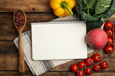 Recipe book surrounded by different ingredients on wooden table, flat lay with space for text. Cooking classes