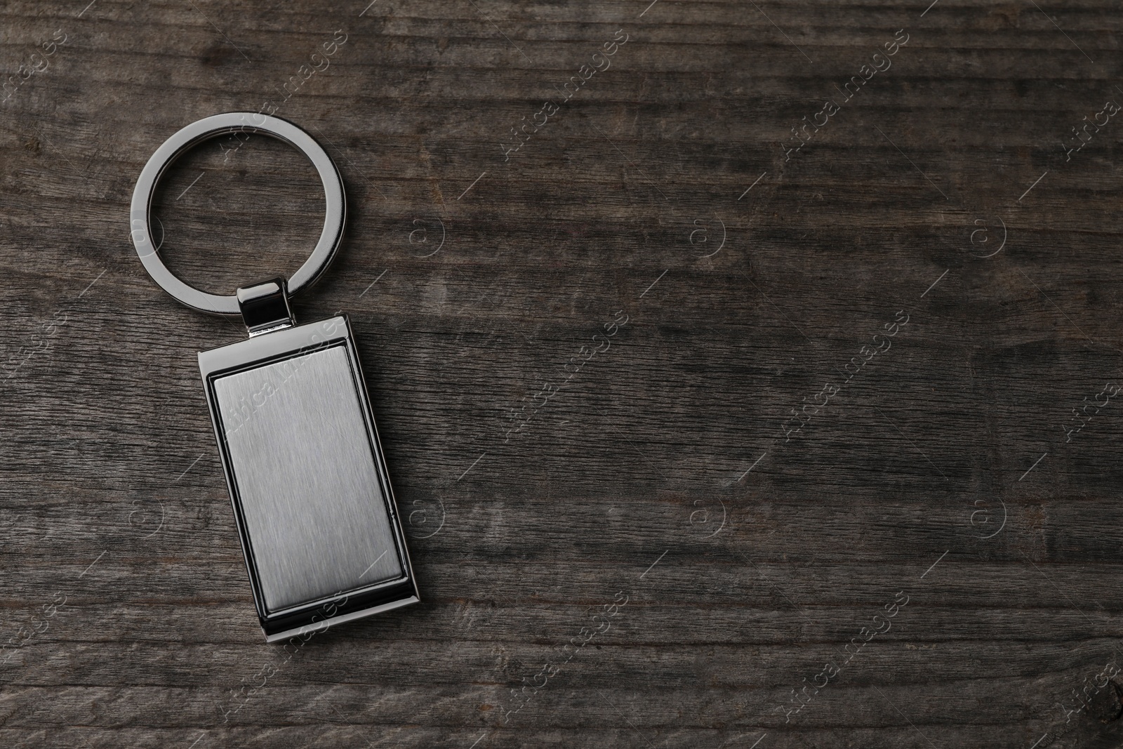 Photo of Metallic keychain on wooden background, top view. Space for text