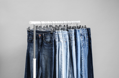 Photo of Rack with different jeans on grey background