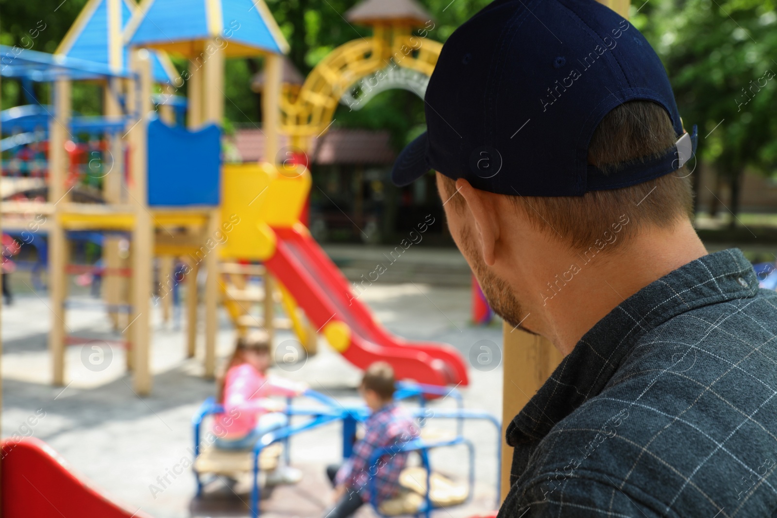 Photo of Suspicious adult man spying on kids at playground, space for text. Child in danger