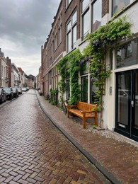 Picturesque view of city street with beautiful buildings and wooden bench