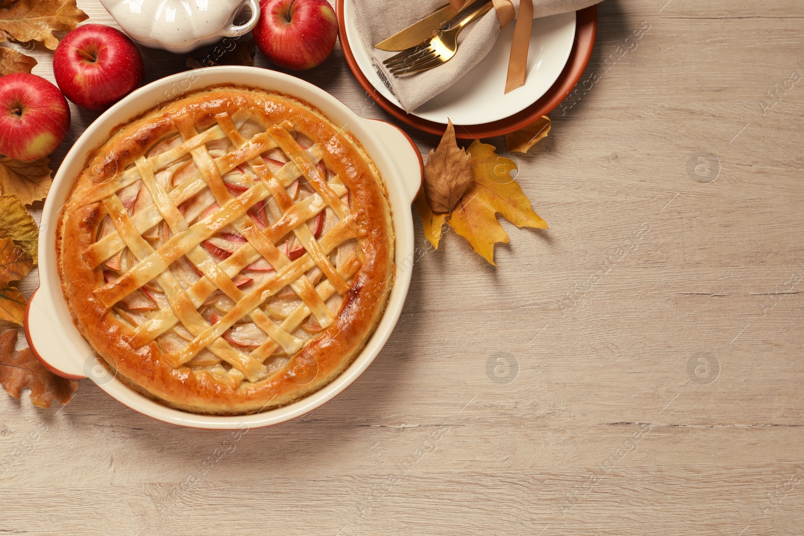 Photo of Delicious homemade apple pie and autumn leaves on wooden table, flat lay with space for text. Thanksgiving Day celebration