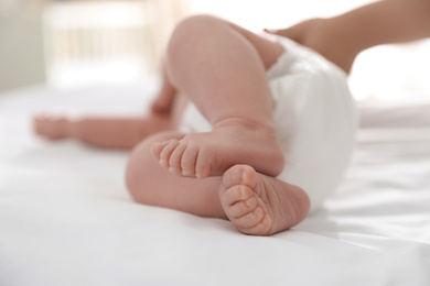 Photo of Cute little baby in diaper on bed, closeup