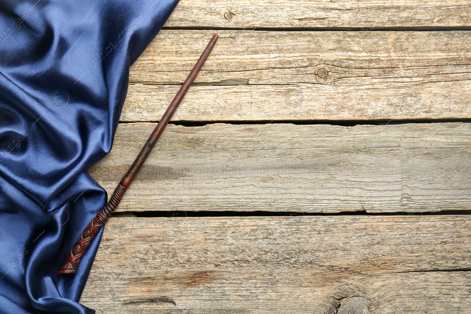 Photo of Old magic wand and fabric on wooden table, top view. Space for text